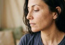 La barriera cutanea spiegata bene: la guida agli approfondimenti di Assenza Primo piano del viso di una donna su sfondo neutro beige, luce naturale morbida, pelle senza trucco.